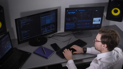 Top view of a specialist IT company for the development of applications for secret spy services. A man looks hard at the screen on which characters are printed in the running line.