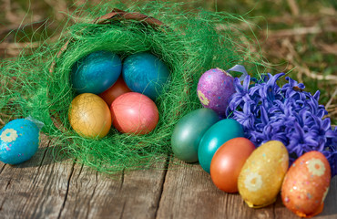 Easter eggs in nest on old wooden background with blue hyacinths flower