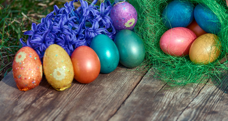 Easter eggs in nest on old wooden background with blue hyacinths flower