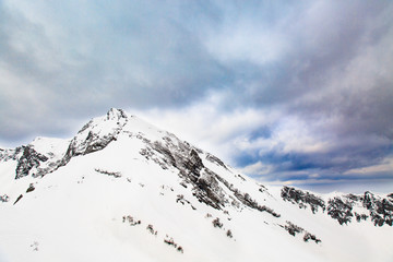 Winter landscape. Snow covered high mountain peaks under cloudy panoramic skies in Europe. Great place for winter sports.