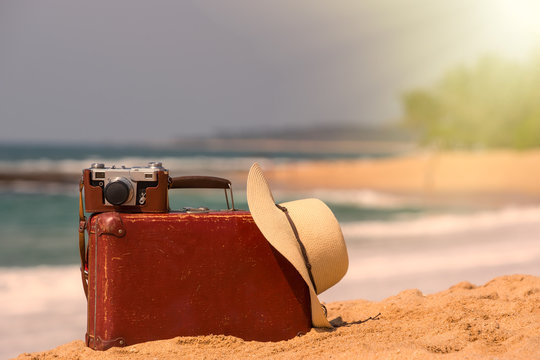 Travel  vintage suitcase and camera on a beach