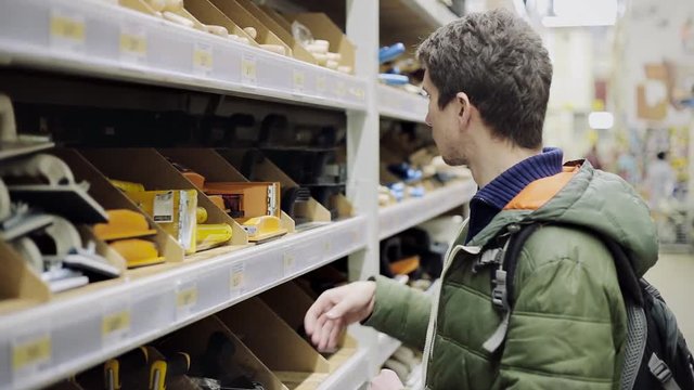 Young man selecting construction pallet in a hardware store or warehouse to make repair