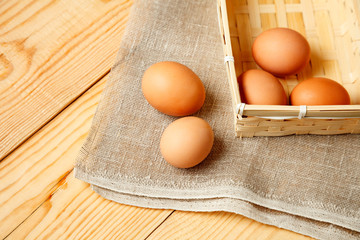 Raw eggs in wicker basket on wooden table