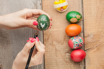 Easter eggs and natural wooden country table with woman hand coloring eggs