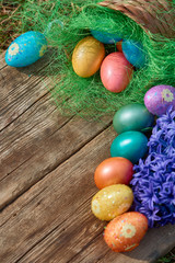 Easter eggs in nest on old wooden background with blue hyacinths flower