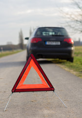 breakdown triangle stands near a broken car