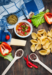 Raw Conchiglioni with minced meat and vegetables on dark wooden background.