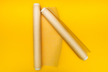 Two rolls of parchment paper on a yellow background.