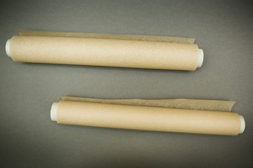 Two rolls of parchment paper on a gray background.