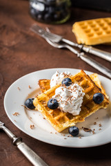 Belgian waffles on white plate on rustic background.