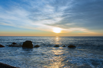 Fototapeta na wymiar Beautiful sunrise on a sea shore with big stones