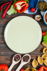 Raw Conchiglioni with minced meat and vegetables on dark wooden background.