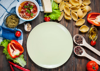 Raw Conchiglioni with minced meat and vegetables on dark wooden background. Top view