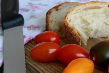 Brotscheiben mit Tomaten, Brotmesser und Küchentuch auf Holztisch