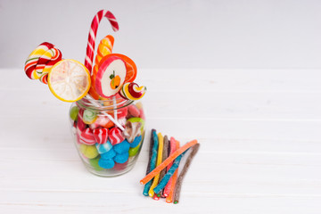 Chewing sweets, bright lollipops with candy cane and jelly candies in the glass can near licorice candies
