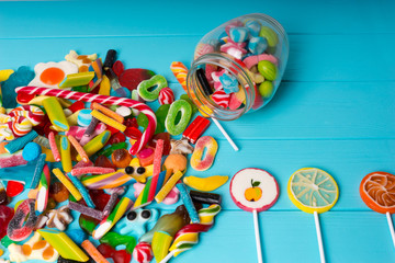 Fototapeta na wymiar View from above on cattered candies and lollipops as fruits near glass can with chewing sweets