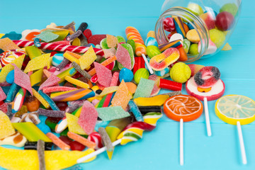 Cattered tasty candies and lollipops as fruits near glass can with chewing sweets