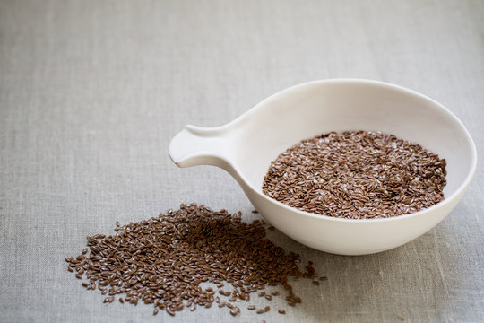 Flax seeds in bowl on linen cloth background 