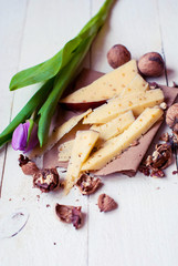 Dutch cheese with fenugreek and walnuts on a wooden table with a tulip.