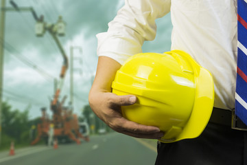 engineer or worker hold in hand yellow helmet ,Engineer and worker discussing blueprint next to electrical substation for workers security in front of construction blur background. Selective focus.