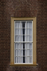 Fototapeta na wymiar Single yellow framed window on red brick wall.