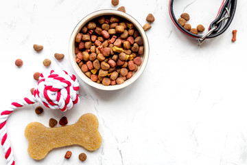 dry dog food in bowl on stone background top view