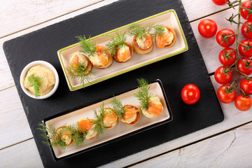 Salmon appetizer with dill dip in puff pastry cake on stone tray