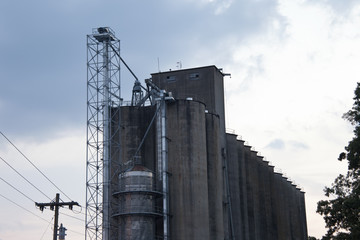 Tall industrial concrete building surrounded by cloudy blue sky