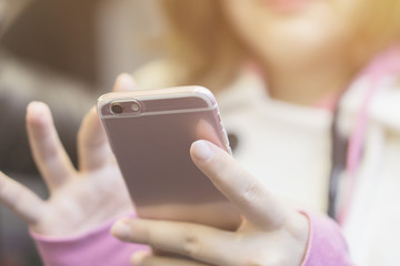 Woman typing text message on smart phone in a cafe.young girl sitting at a table with a coffee using mobile phone.vintage color,selective focus