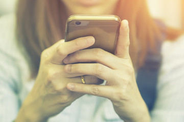 Woman Viewed Through Window Of Cafe Using Mobile Phone,typing text message on smart phone in a cafeteria.young girl sitting at a table with a coffee using tablets pc,vintage color,selective focus