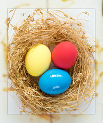 Happy Easter Card - space for text. Easter eggs in nest on rustic wooden background, selective focus image. 