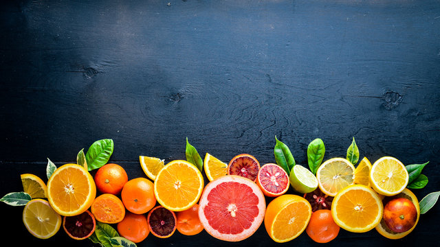 Fresh citrus fruits. Lemon orange, tangerine, lime. On a black background Wooden. Top view.