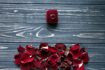 Luxury red rose petals bottom and red velvet box with a ring on the top. Space for text. Postcard wallpaper.