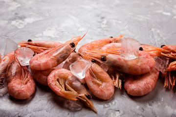 shrimps or prawns and ice on grey concrete background, close up