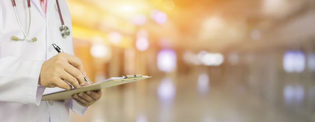 Male Doctor with files and stethoscope on hospital corridor holding clipboard and writing prescription,Doctor,Medical Exam Healthcare and medical concept,test results, registration,banner blackground