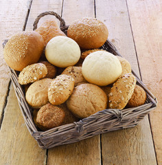 Fresh bakery products wicker basket rough rustic rural plank table background. Different grain seeds light dark organic local business homemade bread. Top view.