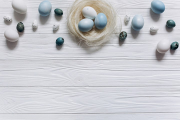 Blue and white Easter  eggs in nest on wooden background.