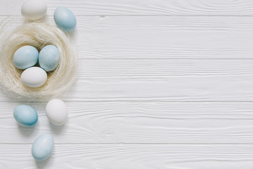 Blue and white Easter  eggs in nest on wooden background.