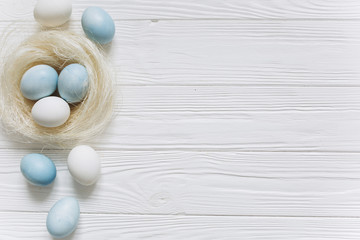 Blue and white Easter  eggs in nest on wooden background.