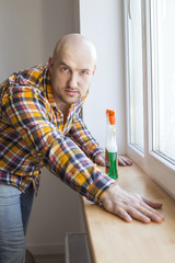 Handsome man cleaning window sill