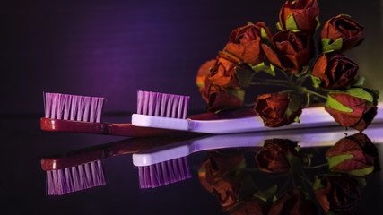 Red and white Tooth brushes with flowers on dark  background