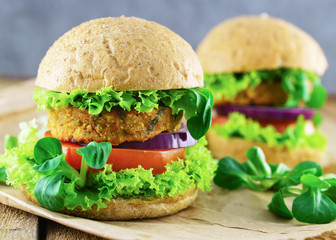 Fresh vegan sandwich with bread ciabatta onion, tomatoes, lettuce, beans cutlets on wooden background.