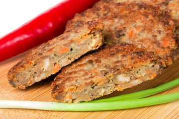 liver pancakes or cutlets with chilli and spring onions on a cutting board close-up isolated white background