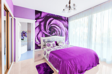 Interior of cozy bedroom in bright violet tones. Large mirrored wardrobe. Wall-papers on a wall.