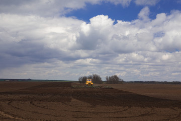 Naklejka premium Agriculture..The tractor prepares the field for sowing wheat in early spring in the steppes of Kalmykia during a thunderstorm.