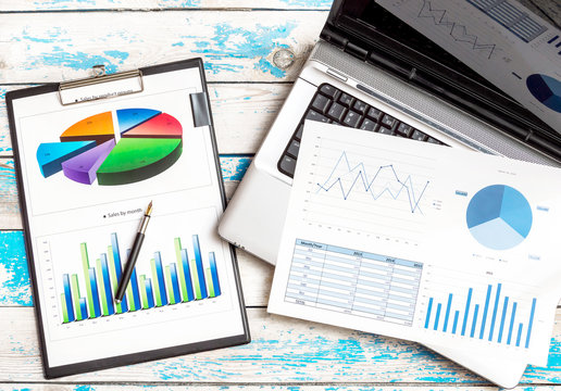 Office workplace. Financial graphs with laptop and pen on the table. Business concept.