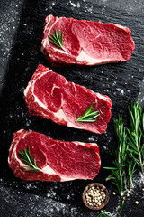 Raw meat, beef steak on black background, top view