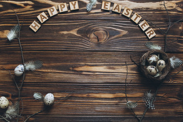 Fototapeta na wymiar Decoration with quail eggs, nest and feathers. Vintage wooden background with sample text Happy Easter.