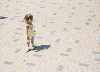 Little curly blonde girl playing outdoors.