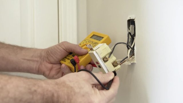 An electrician or homeowner handyman type checking the voltage of a ground fault outlet